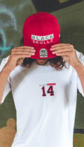 male model wearing red fitted hat with black skullz logo embroidered and brand white tshirt