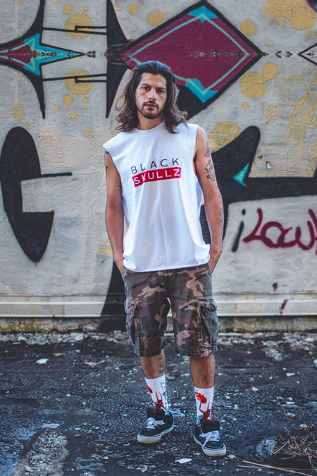 male model wearing white blackskullz brand label tank and camo shorts